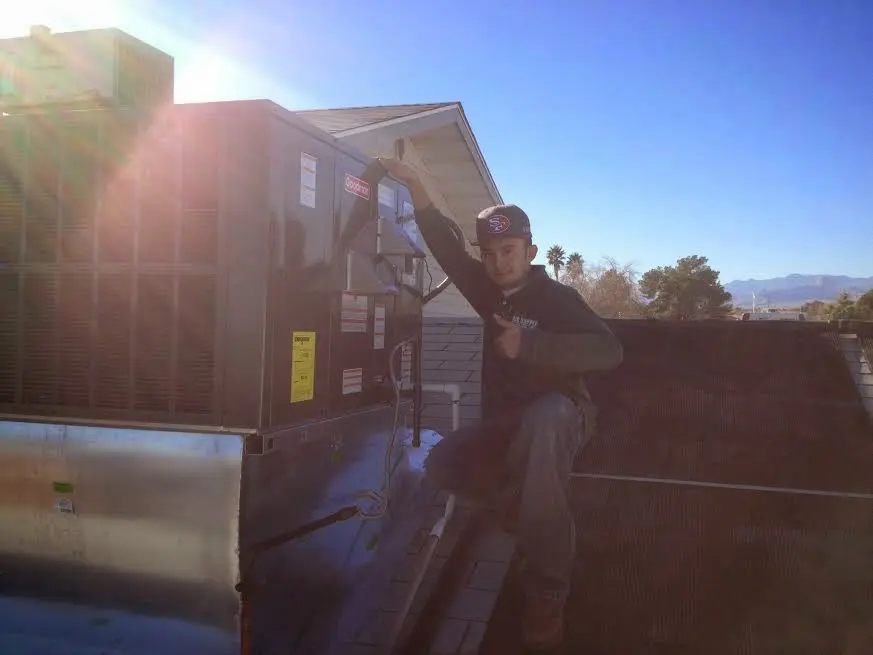HVAC technician performing AC Tune-Up on a rooftop unit in Winston